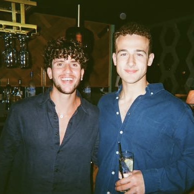 Josh and Nicky, the founders of Make Sh 't Good, smiling together at a bar