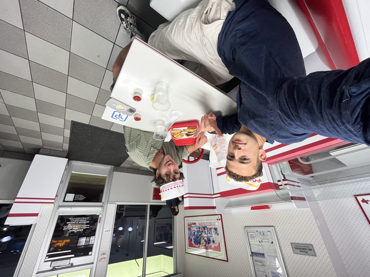 Nicky and Josh in an In-N-Out booth wearing paper hats